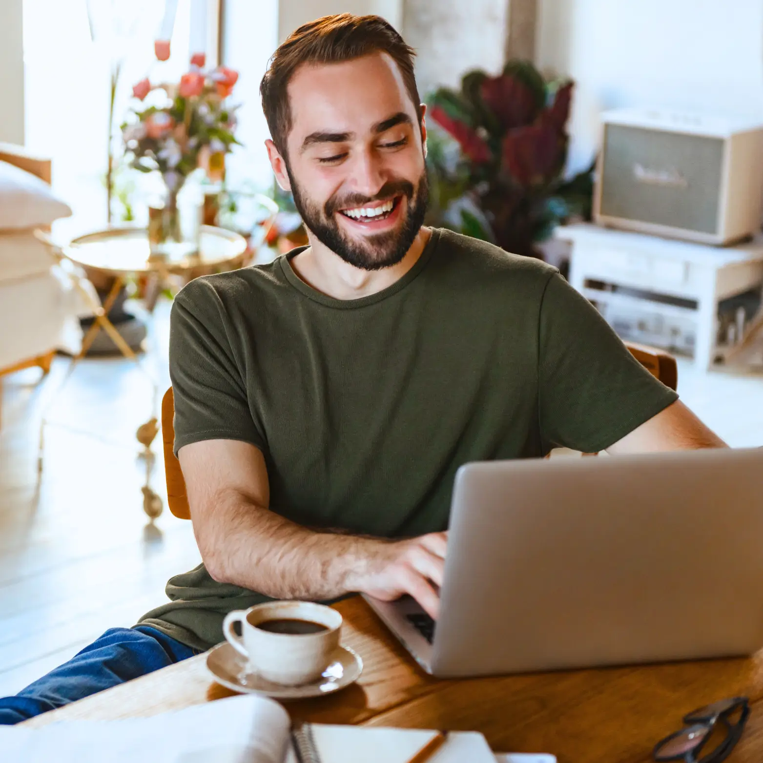 man smiling wearing olive green shirt sitting at his computer during online therapy session